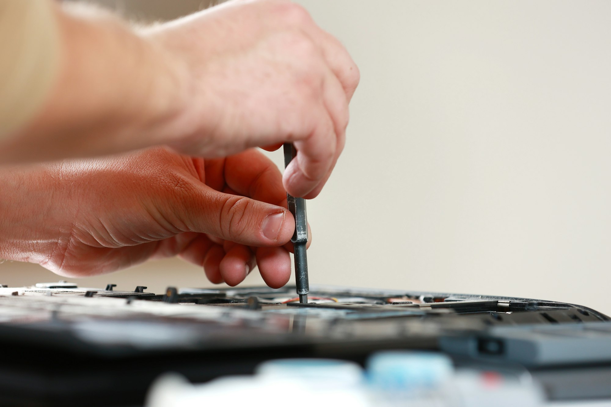 Repaiman with screwdriver fixing disassembled laptop parts. Technical support and fixing gadgets pro